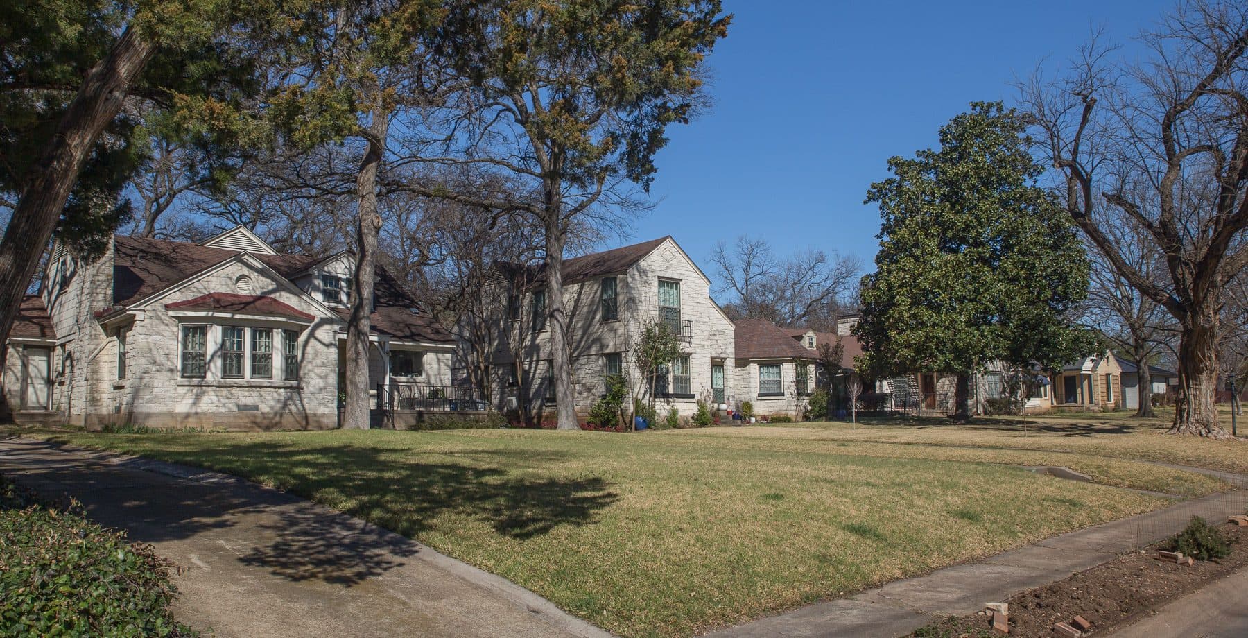 A quiet street of older two-story homes and wide lawns in the Kessler Park neighborhood of Oak Cliff, Dallas.