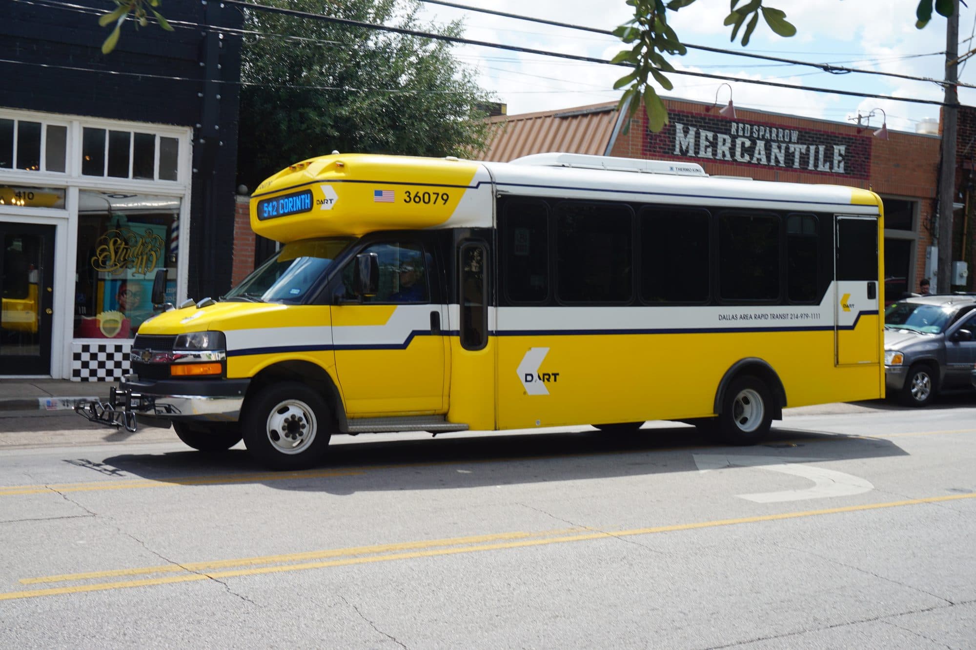 A yellow DART shuttle bus driving through the Bishop Arts District in Oak Cliff.
