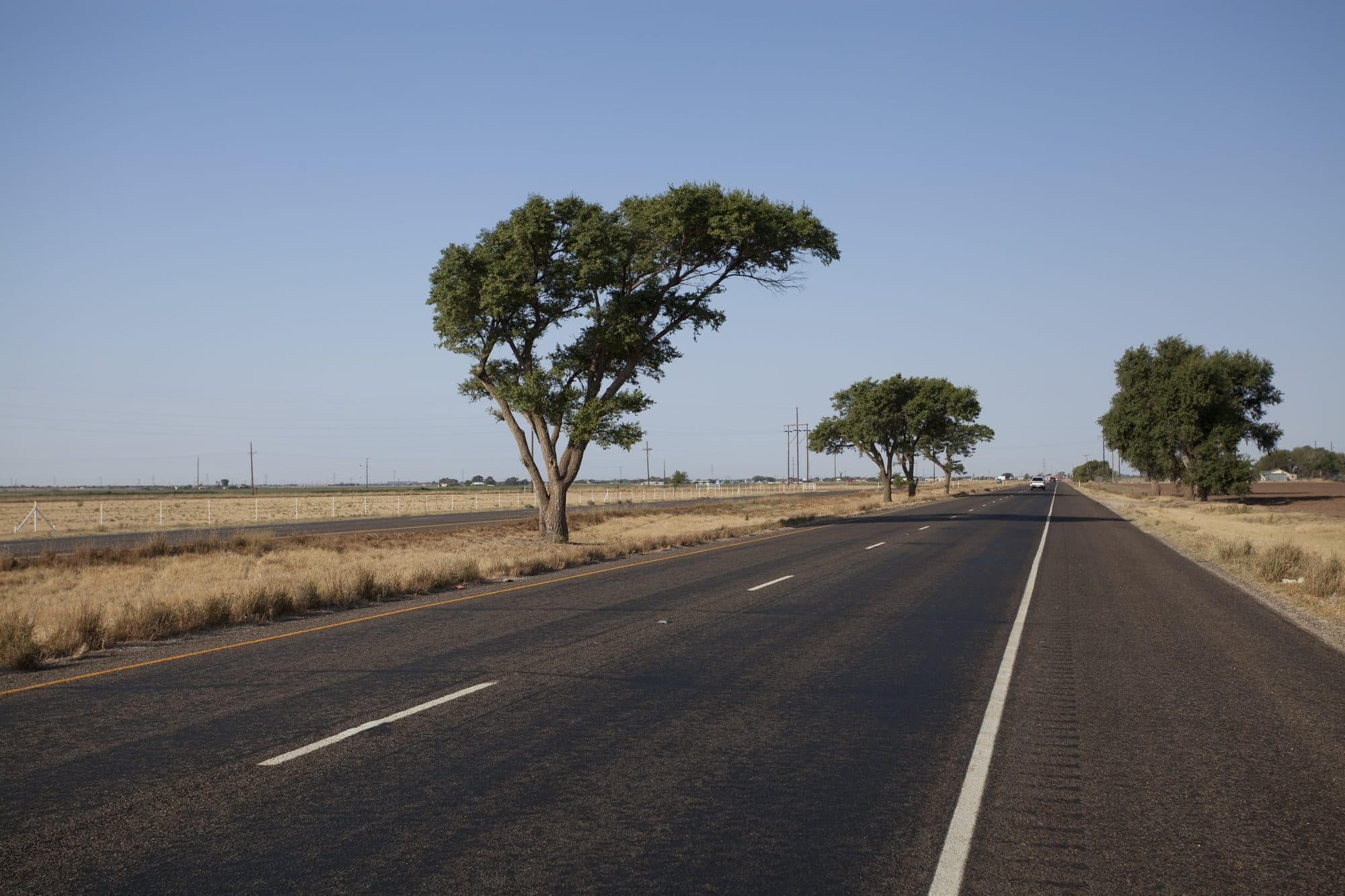 A two-lane US Highway 82 running straight through flat farmland in Lubbock County, Texas.