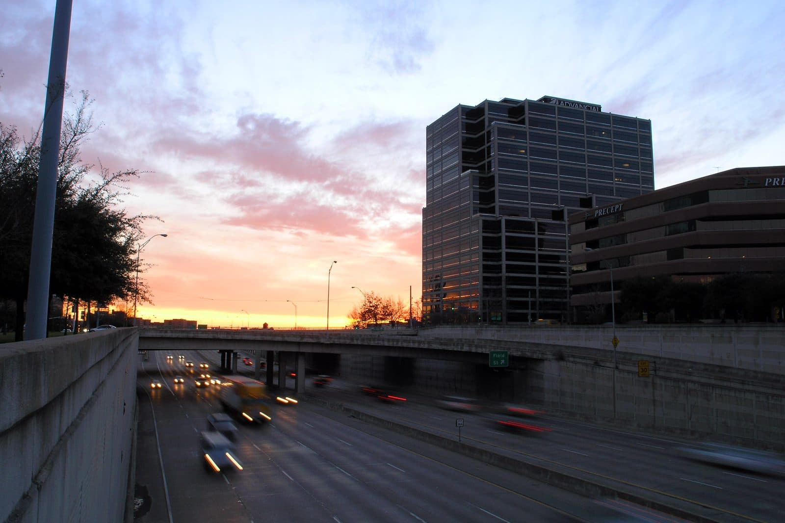 Headlight and taillight trails on Woodall Rodgers Freeway in downtown Dallas at dusk.