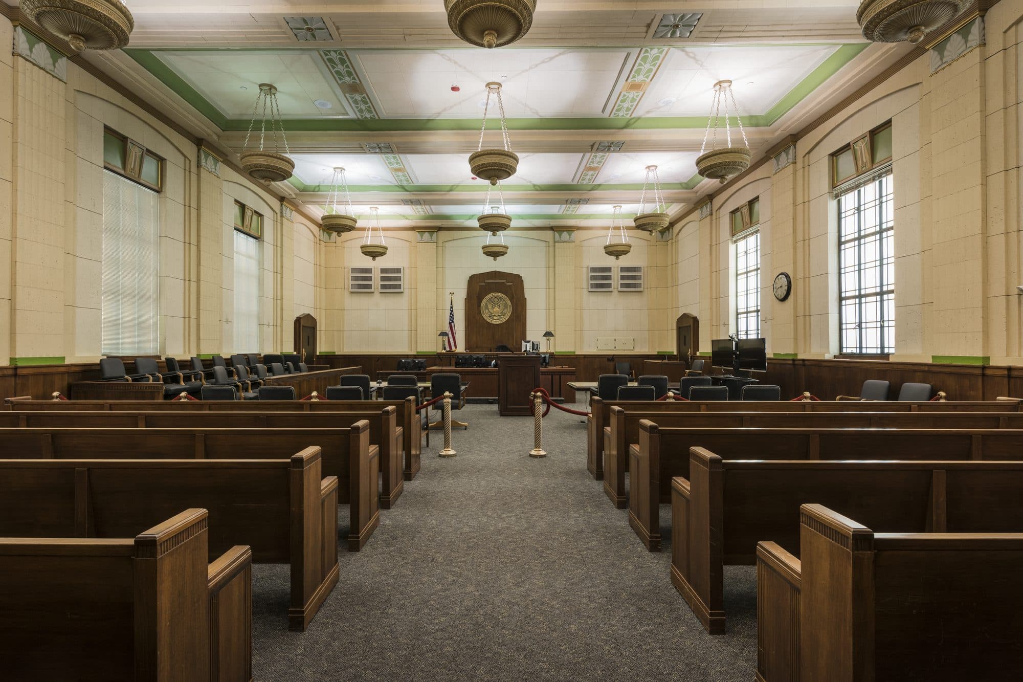 An empty federal courtroom in El Paso, with rows of wooden benches facing the judge's bench.