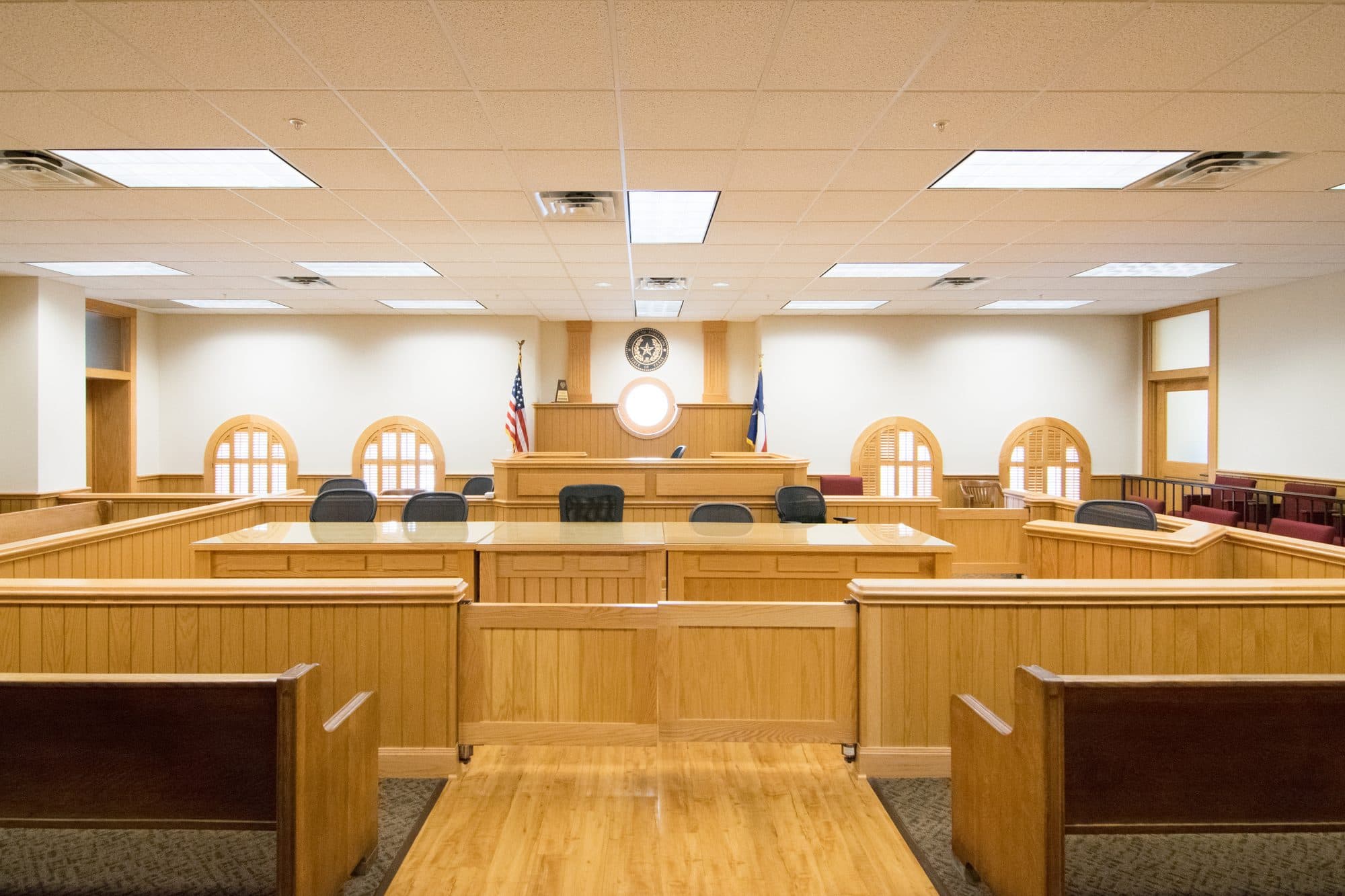 An empty Texas county courtroom with wooden pews, counsel tables and the judge's bench.
