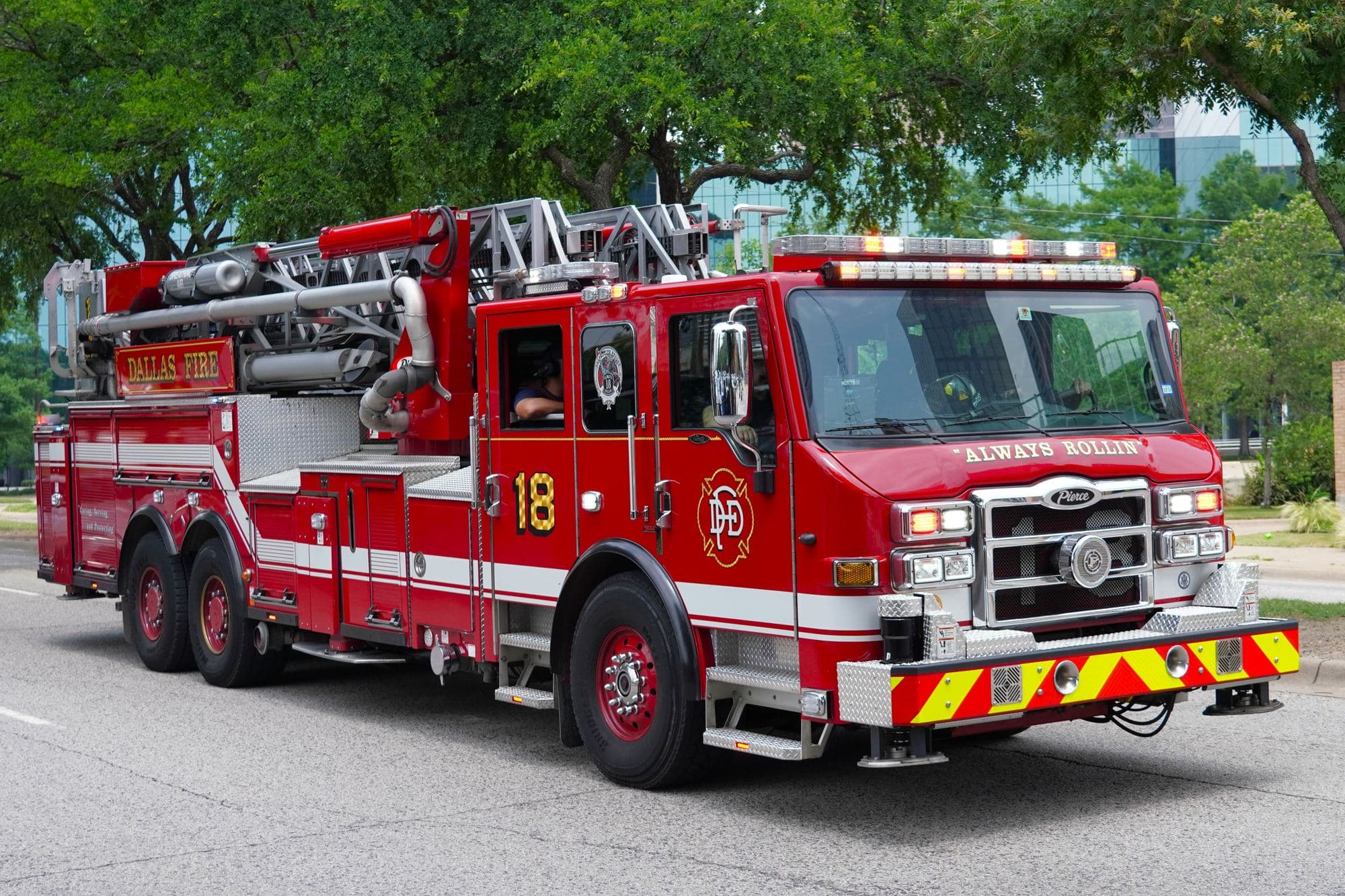 A red Dallas Fire-Rescue ladder truck driving down a city street.