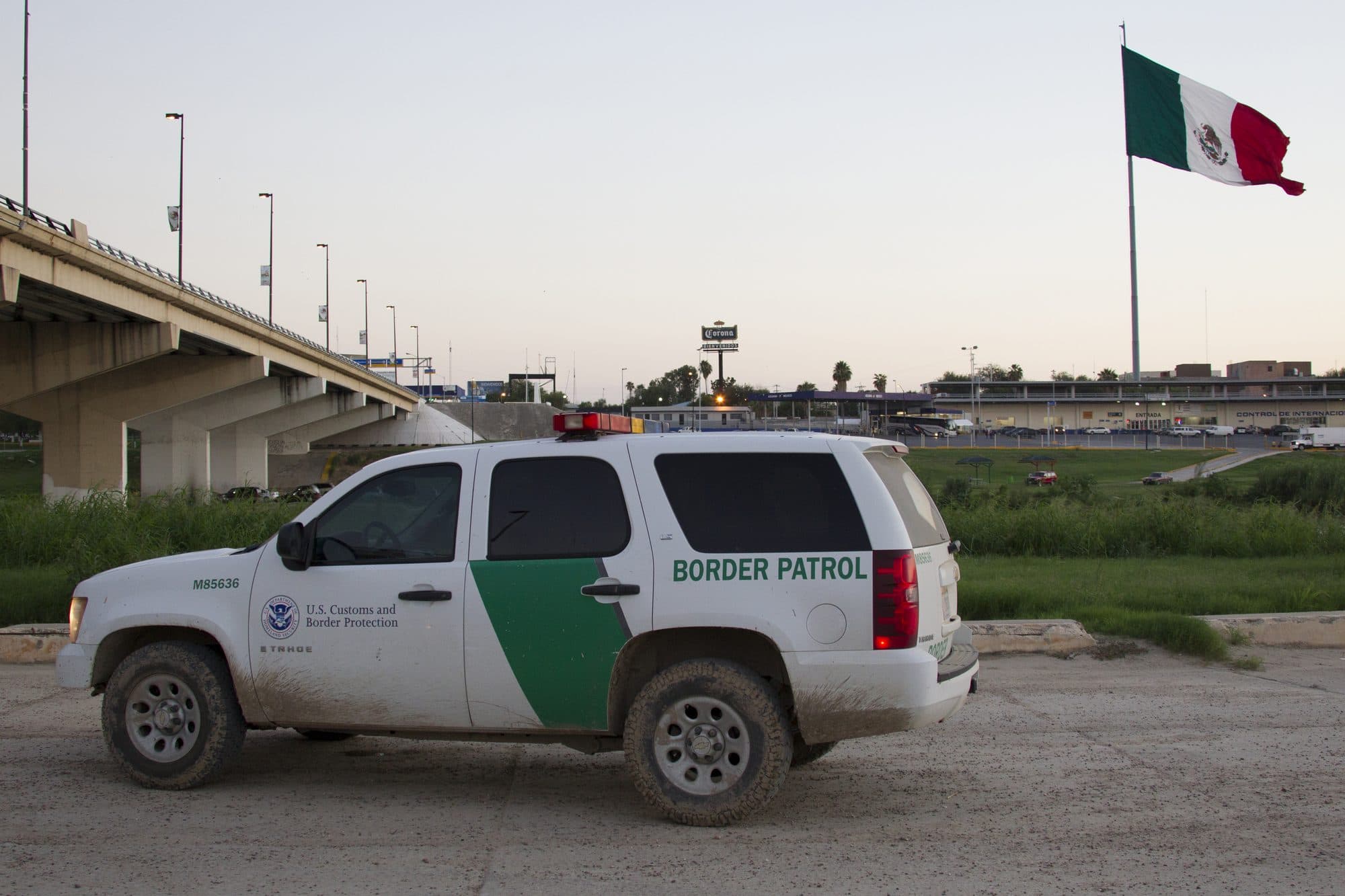 A Border Patrol vehicle parked near the international bridge in Laredo, Texas, with a Mexican flag across the river.