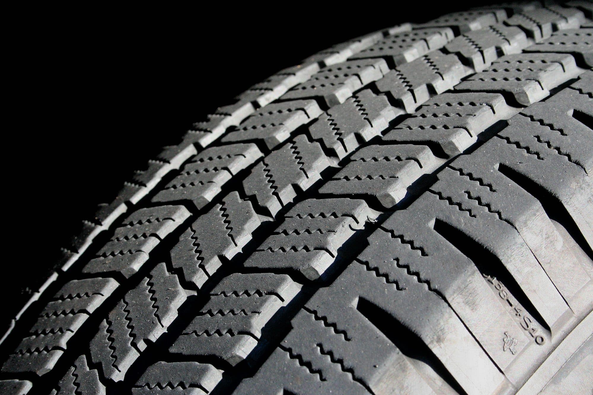 Close-up of the tread on a car tire against a black background.