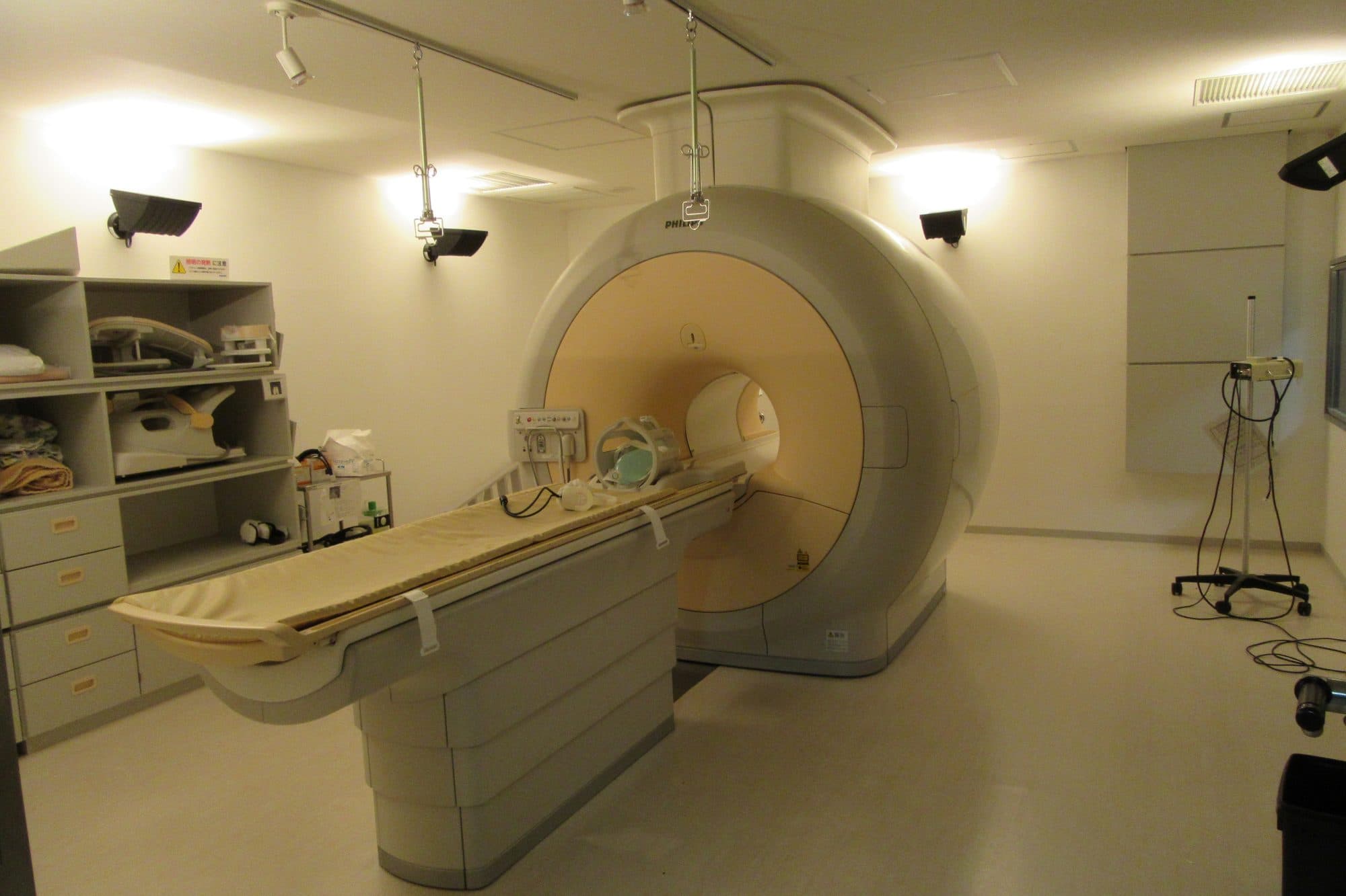 An empty hospital room with an MRI scanner and its patient table.